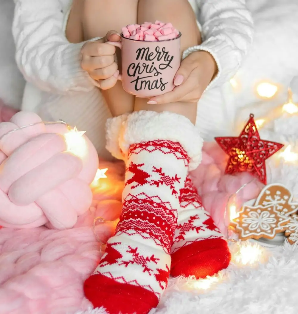 Feet in red and white Christmas socks next to a mug of hot cocoa