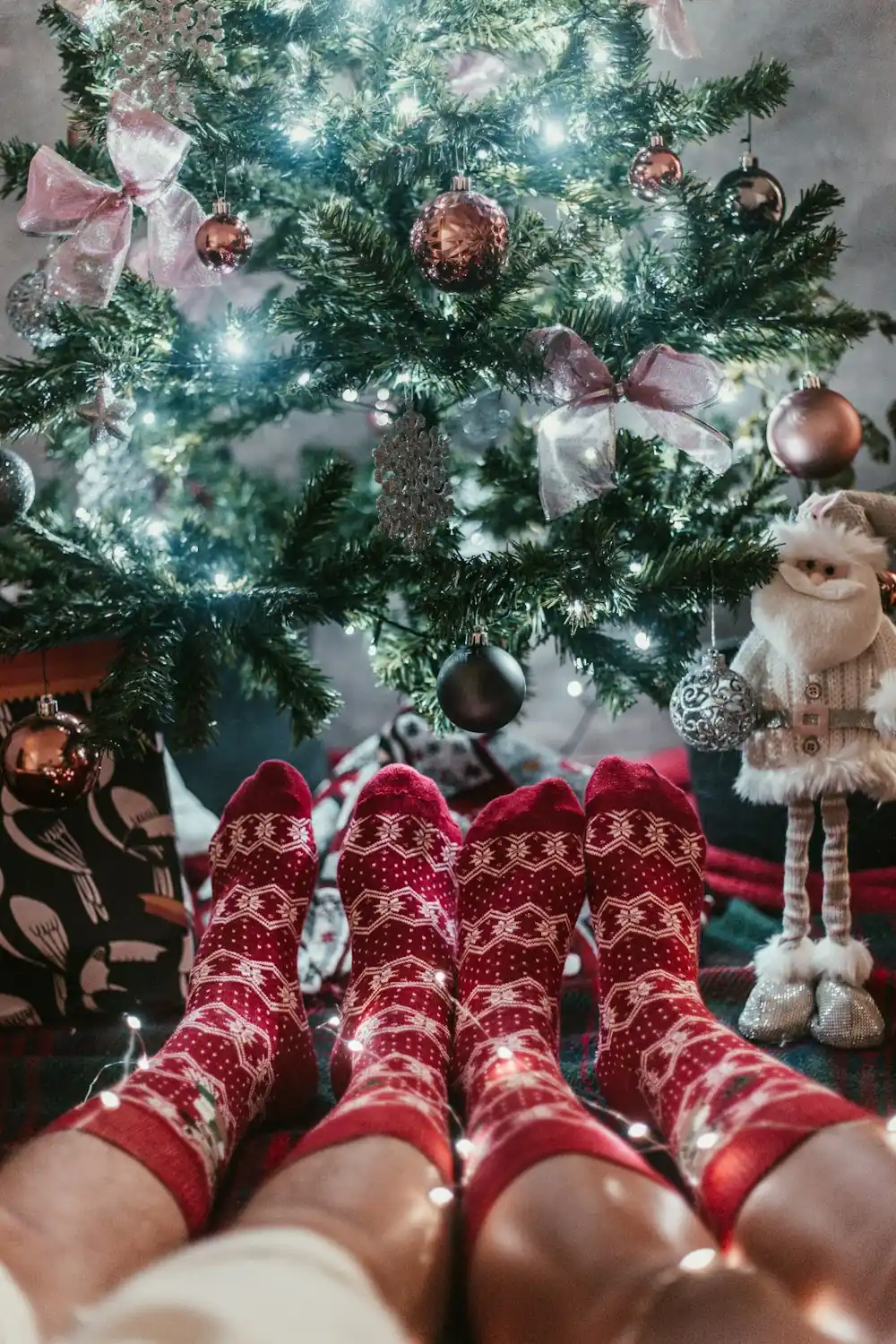 Feet in matching red and white Christmas socks under a Christmas tree